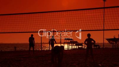 Children playing volleyball on the beach at sunset