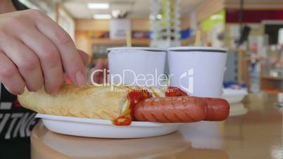 People eating hot dogs with coffee at table in convenience store