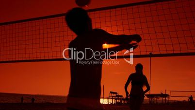 Friends having fun play beach volleyball at sunset