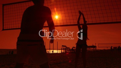 Silhouettes of beach volleyball players at sunset