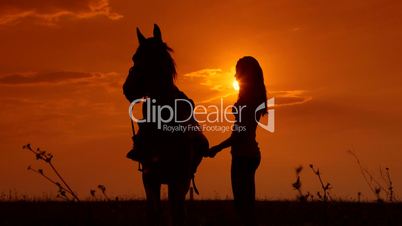 Female rider riding horse to horizon at sunset