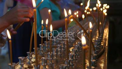 Faithful people lighting prayer candles in the church close-up