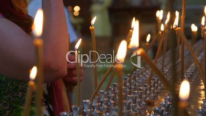 Woman lighting prayer candle in Christian Orthodox Church