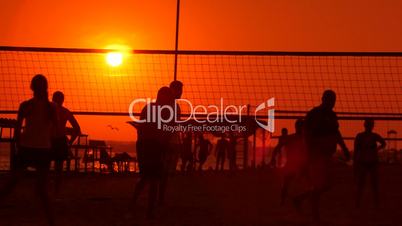 Public beach with a volleyball courts and players silhouettes in the sun