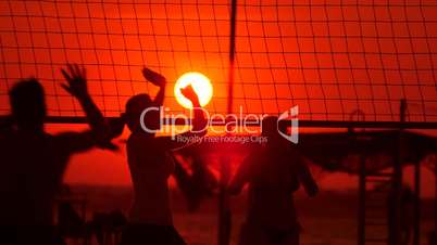 Young people group have fun and play beach volleyball at sunset