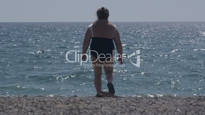 Overweight senior woman walking on the beach