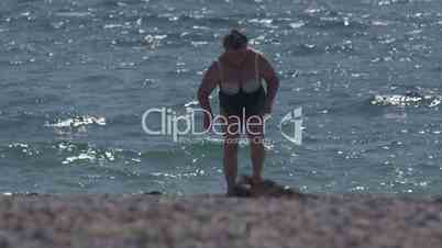Overweight senior woman in swimsuit after swimming on the beach