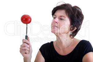Woman with knife looks at skewered tomato