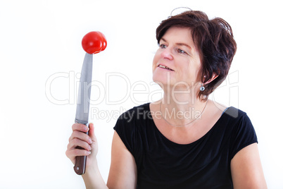 Woman with knife looks at skewered tomato