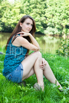 Woman sitting alone in the park by the lake