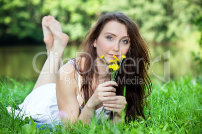 Woman with small bouquet of flowers lying in the park