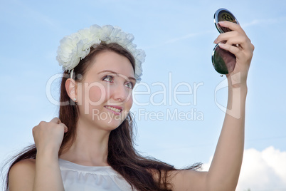 Woman looks at herself in the compact mirror