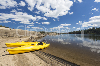 Pair of Yellow Kayaks on Beautiful Mountain Lake Shore.