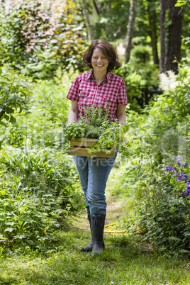Junge Frau mit Kräutern im Garten, young woman with herbs in a