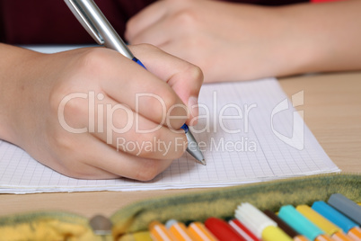 Schüler schreibt in sein Heft mit Stift in der Schule