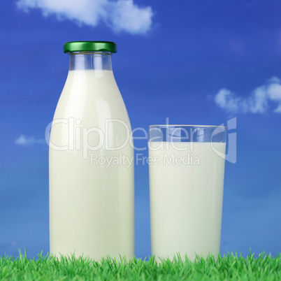 Milch in der Flasche und im Glas auf einer grünen Wiese