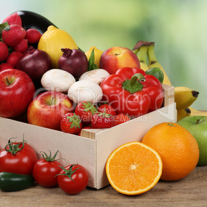 Früchte und Gemüse wie Orangen, Tomaten und Äpfel in Kiste