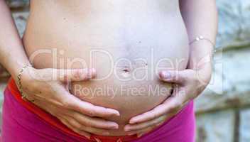 Pregnant woman embracing belly with her hands