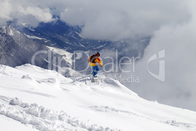 Snowboarder on off-piste slope an mountains in fog