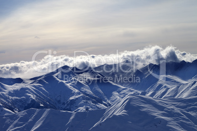 Snowy mountains in mist at winter evening