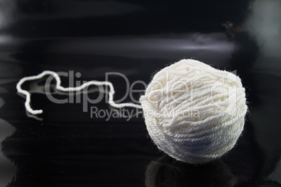 The white ball of wool thread on a black background