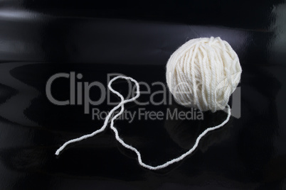 The white ball of wool thread on a black background