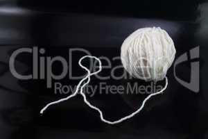The white ball of wool thread on a black background