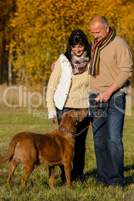 Couple with dog in sunny autumn park