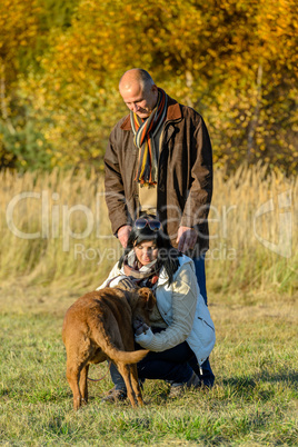 Couple playing with dog sunny autumn park