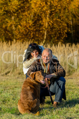 Cheerful couple with dog in autumn countryside