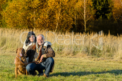 Cheerful couple with dog in autumn countryside