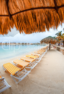 Row of beach chairs and straw umbrellas along the ocean