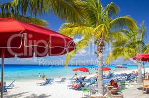 Tropical beach with relaxing people and colourful umbrellas