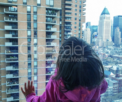 Baby looking to city skyline through a big window