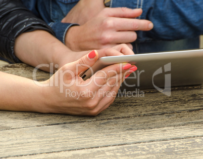 Girls relaxing using their tablet on a table outdoor. Hands deta