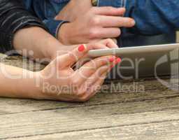 Girls relaxing using their tablet on a table outdoor. Hands deta