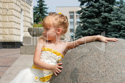 Small girl near a marble ball in a summer day