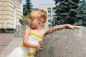 Small girl near a marble ball in a summer day