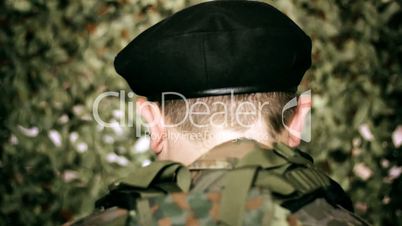 back of the head of a soldier in front of camouflage net