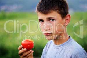 Young boy eating fresh tomato
