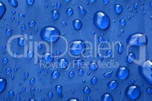 Closeup of rain drops on a blue umbrella