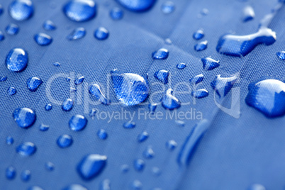 Closeup of rain drops on a blue umbrella