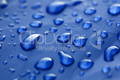 Closeup of rain drops on a blue umbrella