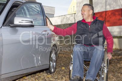 Man in a wheelchair in the fall next to their car