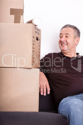 Man sitting on the sofa next to his moving boxes