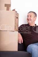 Man sitting on the sofa next to his moving boxes