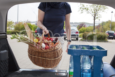 Woman lifts filled basket in the car