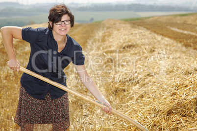 Women farmers with pitchfork works on the field