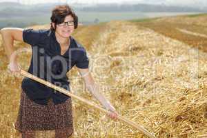 Women farmers with pitchfork works on the field