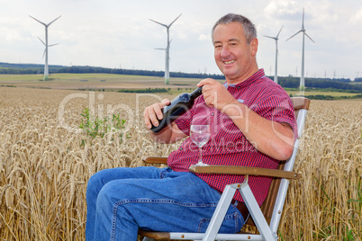 Man sitting with wine bottle in cornfield